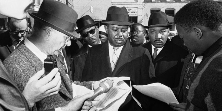 Chief Deputy U.S. Marshal H. Stanley Fountain, left, reads court order to Dr. Martin Luther King, right, and Ralph Abernathy, center, as they arrive at court house in Selma, Alabama on Jan. 25, 1965, to urge African Americans to register to vote.